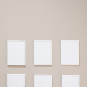 Empty white photo frames hanging on gray wall